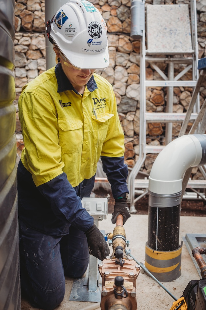 Girl in tradie uniform plumbing.